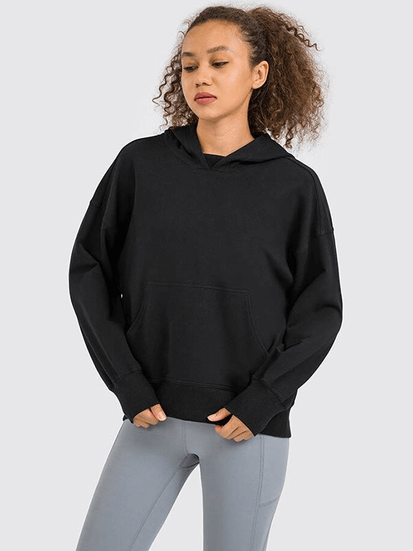 Woman modeling black batwing sleeves hoodie for running, featuring a relaxed fit and front pocket, perfect for stylish outdoor activities.